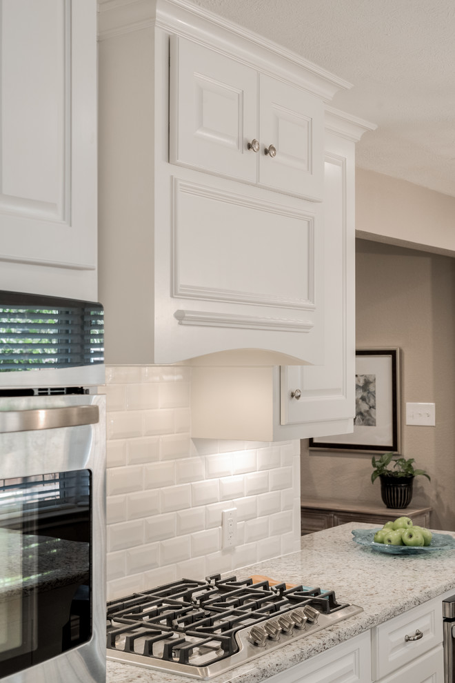 Enclosed kitchen - mid-sized transitional galley medium tone wood floor enclosed kitchen idea in Dallas with an undermount sink, raised-panel cabinets, white cabinets, granite countertops, white backsplash, subway tile backsplash, stainless steel appliances and a peninsula