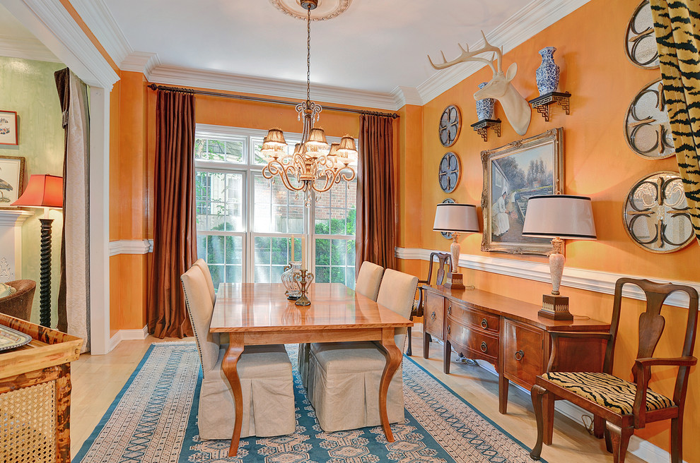 Traditional dining room in Chicago with orange walls and light hardwood floors.