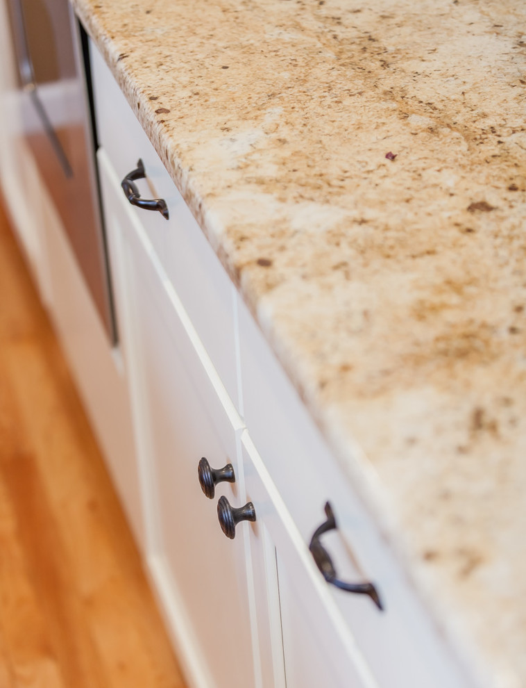 Enclosed kitchen - mid-sized transitional u-shaped light wood floor enclosed kitchen idea in Boston with a double-bowl sink, recessed-panel cabinets, white cabinets, granite countertops, beige backsplash, stone tile backsplash, stainless steel appliances and an island