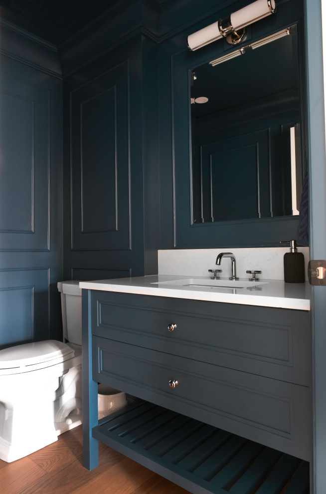Inspiration för små klassiska vitt toaletter, med skåp i shakerstil, blå skåp, en toalettstol med separat cisternkåpa, blå väggar, mellanmörkt trägolv, ett undermonterad handfat och bänkskiva i kvarts