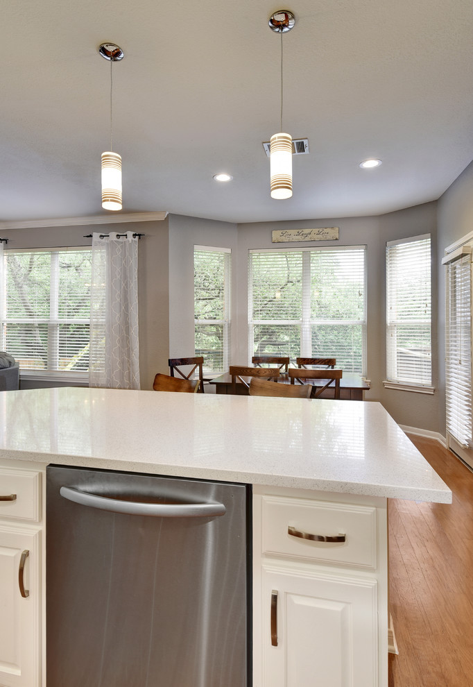 Inspiration for a mid-sized transitional u-shaped light wood floor eat-in kitchen remodel in Austin with an undermount sink, white cabinets, quartz countertops, white backsplash, stone slab backsplash, stainless steel appliances, a peninsula and raised-panel cabinets