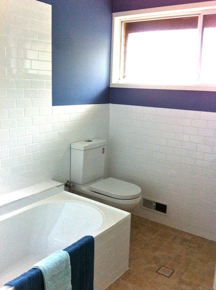 This is an example of a small contemporary 3/4 bathroom in Sydney with a drop-in tub, a shower/bathtub combo, a one-piece toilet, white tile, porcelain tile, blue walls and ceramic floors.