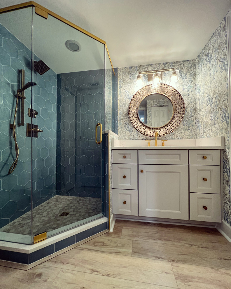 Источник вдохновения для домашнего уюта: ванная комната среднего размера в морском стиле с фасадами с утопленной филенкой, белыми фасадами, угловым душем, унитазом-моноблоком, синей плиткой, керамогранитной плиткой, синими стенами, полом из винила, душевой кабиной, накладной раковиной, столешницей из искусственного кварца, бежевым полом, душем с распашными дверями, белой столешницей, нишей, встроенной тумбой и обоями на стенах