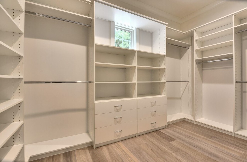This is an example of a mid-sized transitional walk-in wardrobe in San Francisco with white cabinets, light hardwood floors and brown floor.