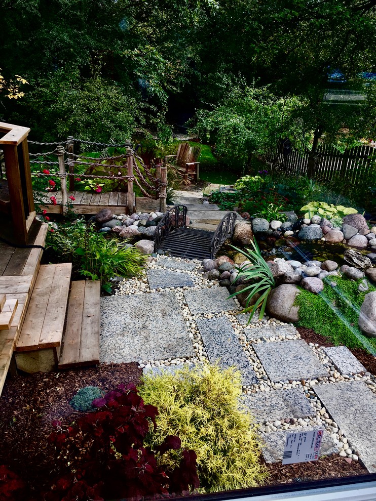 Mid-sized modern sloped partial sun formal garden in Chicago with with pond and natural stone pavers for summer.