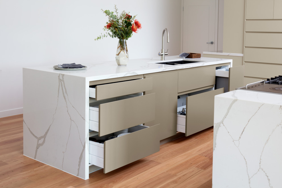 Example of a huge minimalist galley light wood floor eat-in kitchen design in Brisbane with an undermount sink, beige cabinets, quartz countertops, stainless steel appliances, two islands and white countertops