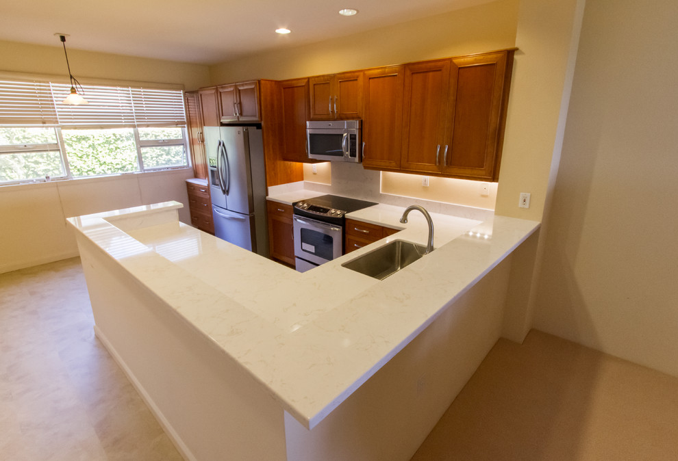 This is an example of a mid-sized asian u-shaped eat-in kitchen in Hawaii with an undermount sink, recessed-panel cabinets, medium wood cabinets, white splashback, stone slab splashback, stainless steel appliances, no island, quartz benchtops, linoleum floors and beige floor.