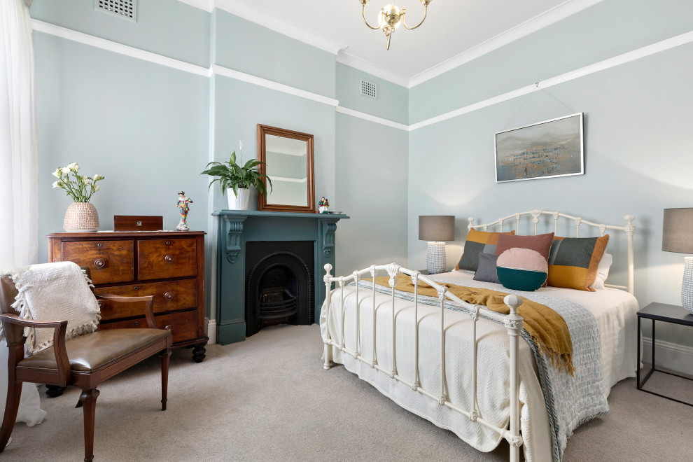 На фото: гостевая спальня (комната для гостей) в викторианском стиле с стандартным камином и фасадом камина из дерева с