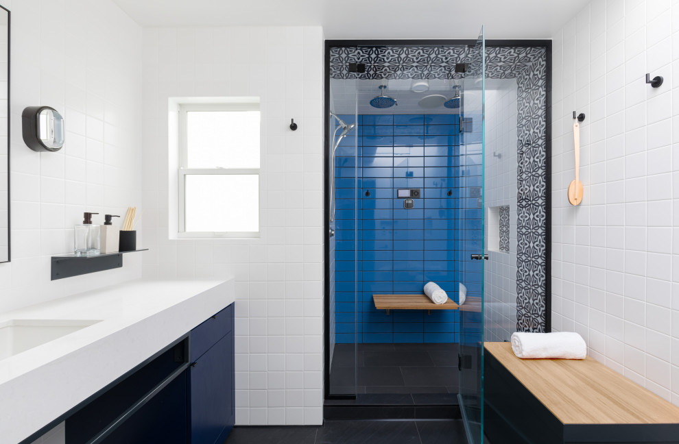 Mid-sized contemporary 3/4 bathroom in San Francisco with flat-panel cabinets, blue cabinets, an alcove shower, blue tile, porcelain tile, porcelain floors, an undermount sink, black floor, a hinged shower door, white benchtops, a niche, a shower seat, a single vanity and a built-in vanity.