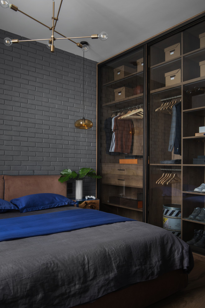 Cette photo montre une petite chambre parentale industrielle avec un mur gris, un sol en carrelage de porcelaine, un sol marron et un mur en parement de brique.