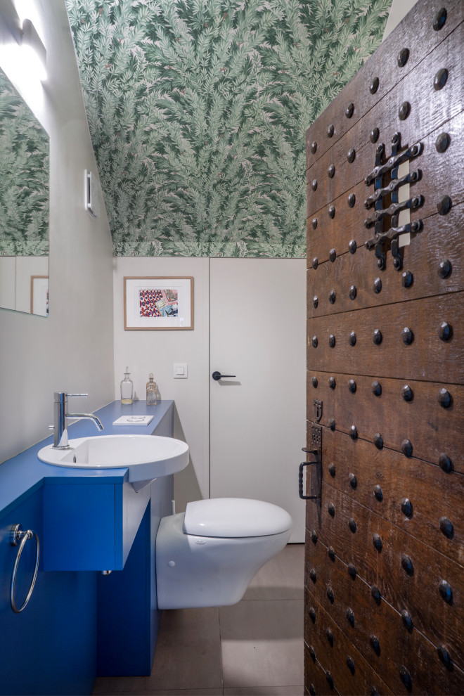 На фото: ванная комната в современном стиле с синими фасадами, инсталляцией, белыми стенами, душевой кабиной, консольной раковиной, синей столешницей, тумбой под одну раковину и потолком с обоями с