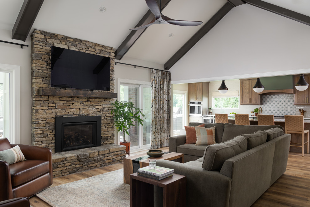 Living room - transitional medium tone wood floor, brown floor, exposed beam and vaulted ceiling living room idea in Louisville with gray walls, a standard fireplace and a wall-mounted tv