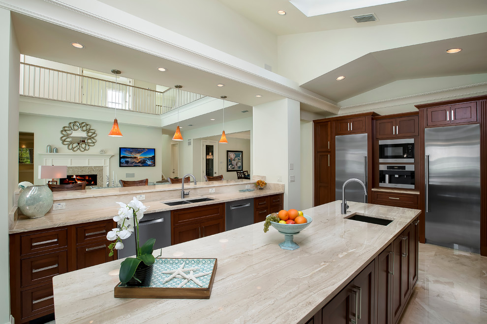 Inspiration for a large tropical u-shaped open plan kitchen in Miami with a drop-in sink, recessed-panel cabinets, medium wood cabinets, granite benchtops, stainless steel appliances, porcelain floors and with island.