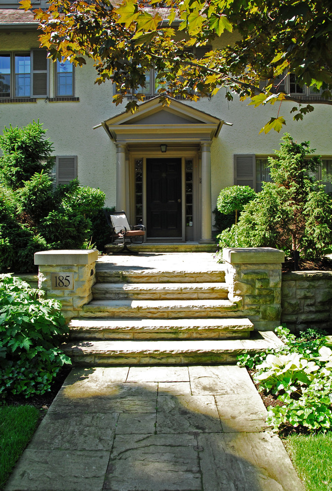 Large traditional front yard partial sun garden in Toronto with a retaining wall and natural stone pavers for fall.