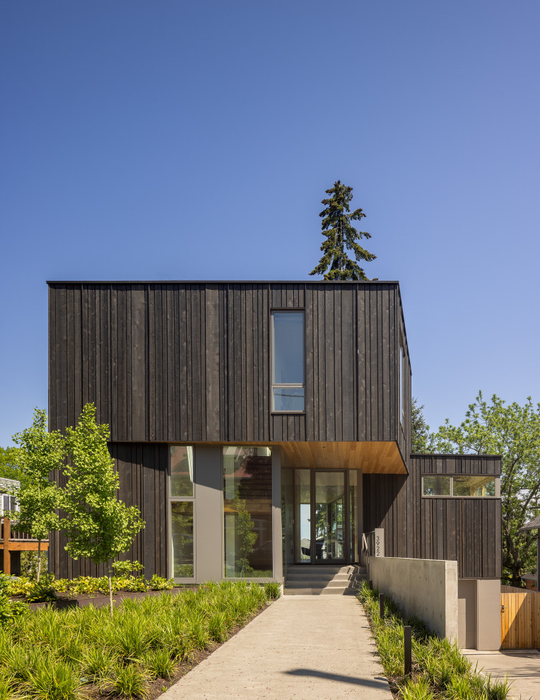 Inspiration for a mid-sized modern three-storey brown house exterior in Seattle with wood siding, a flat roof and board and batten siding.