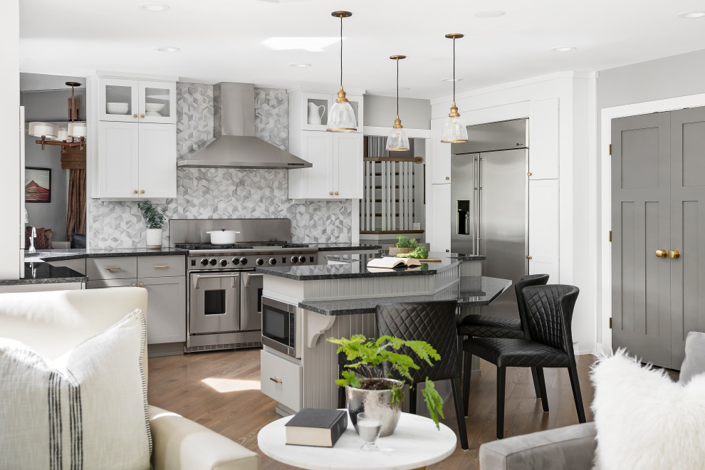 Inspiration for a large transitional open plan kitchen in Chicago with an undermount sink, shaker cabinets, white cabinets, granite benchtops, grey splashback, marble splashback, stainless steel appliances, medium hardwood floors, with island and black benchtop.