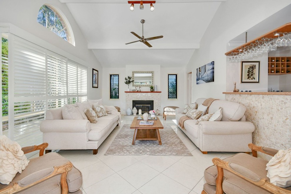 Photo of a large open concept living room in Sunshine Coast with a home bar, white walls, a standard fireplace, a tile fireplace surround, beige floor and no tv.