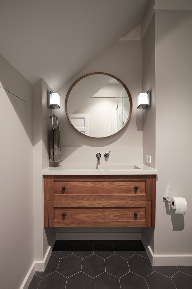Design ideas for a transitional 3/4 bathroom in San Francisco with shaker cabinets, medium wood cabinets, a corner shower, a one-piece toilet, white tile, subway tile, grey walls, porcelain floors, a wall-mount sink, engineered quartz benchtops, grey floor and a hinged shower door.