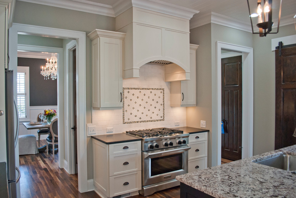 Kitchen - mid-sized transitional medium tone wood floor kitchen idea with an undermount sink, recessed-panel cabinets, white cabinets, granite countertops, white backsplash, subway tile backsplash, stainless steel appliances and an island