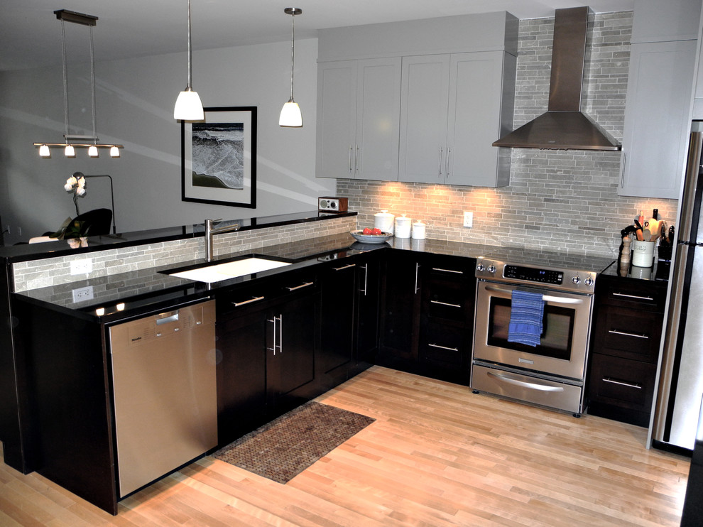 Inspiration for a mid-sized modern l-shaped open plan kitchen in Ottawa with a drop-in sink, beaded inset cabinets, black cabinets, granite benchtops, beige splashback, cement tile splashback, stainless steel appliances, light hardwood floors and a peninsula.