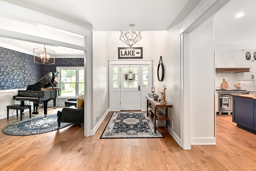 Inspiration for an expansive transitional foyer in Milwaukee with white walls, vinyl floors, a single front door, a white front door, brown floor and wallpaper.