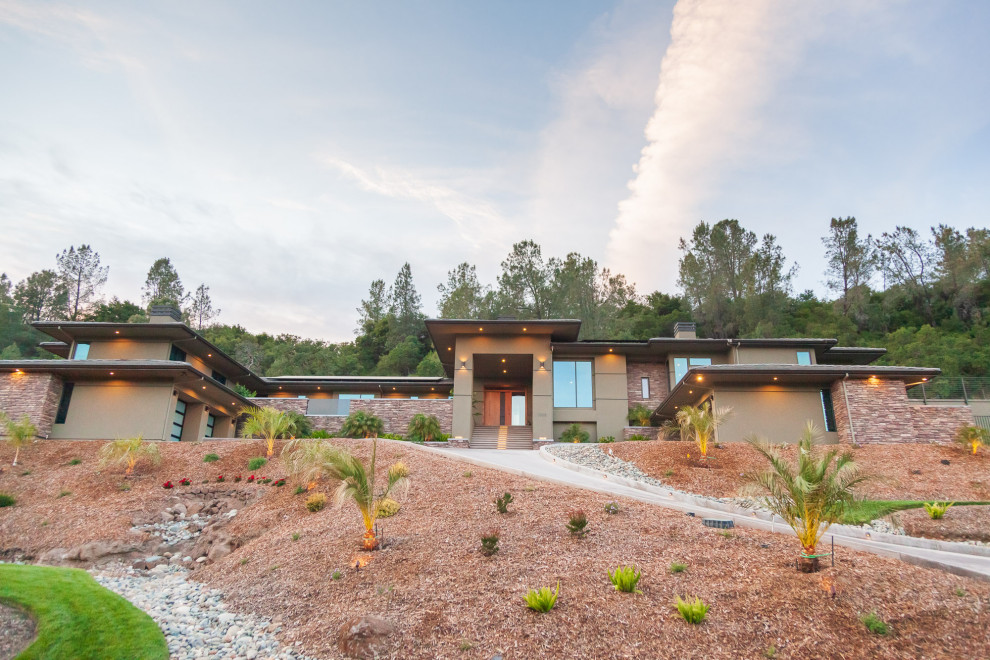 Large green split-level stucco house exterior photo with a hip roof and a tile roof