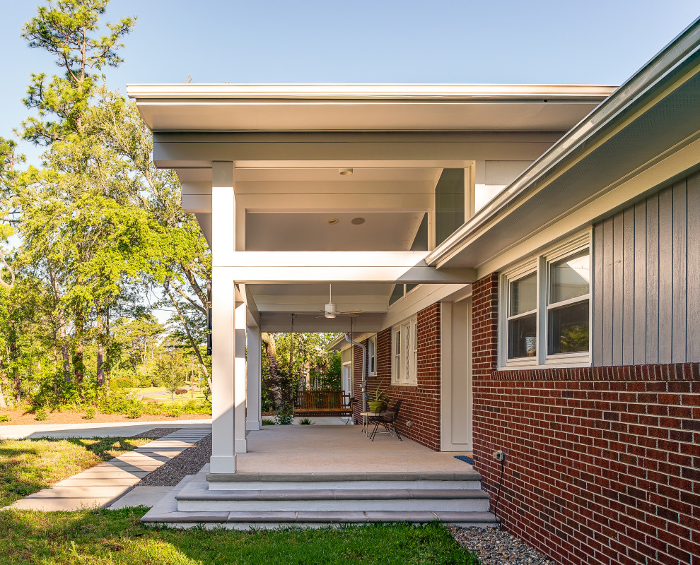 Mid-sized mid-century modern concrete paver front porch idea in Other with a roof extension