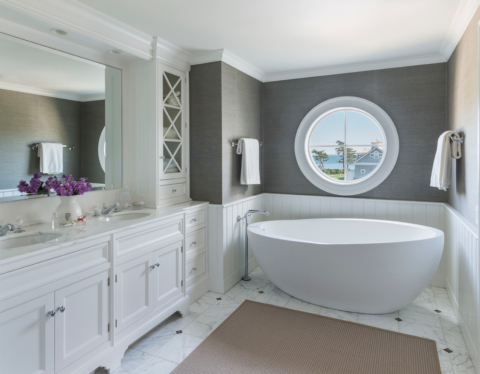Design ideas for a beach style bathroom in Providence with recessed-panel cabinets, white cabinets, a freestanding tub and grey walls.