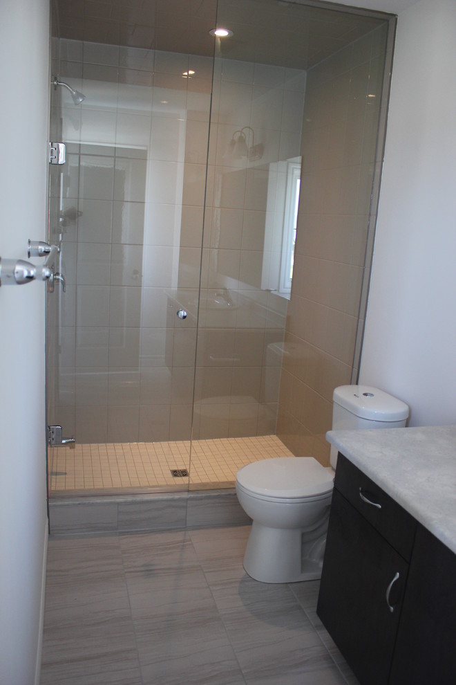 Small contemporary bathroom in Toronto with flat-panel cabinets, dark wood cabinets, an alcove shower, a one-piece toilet, gray tile, ceramic tile, white walls and ceramic floors.