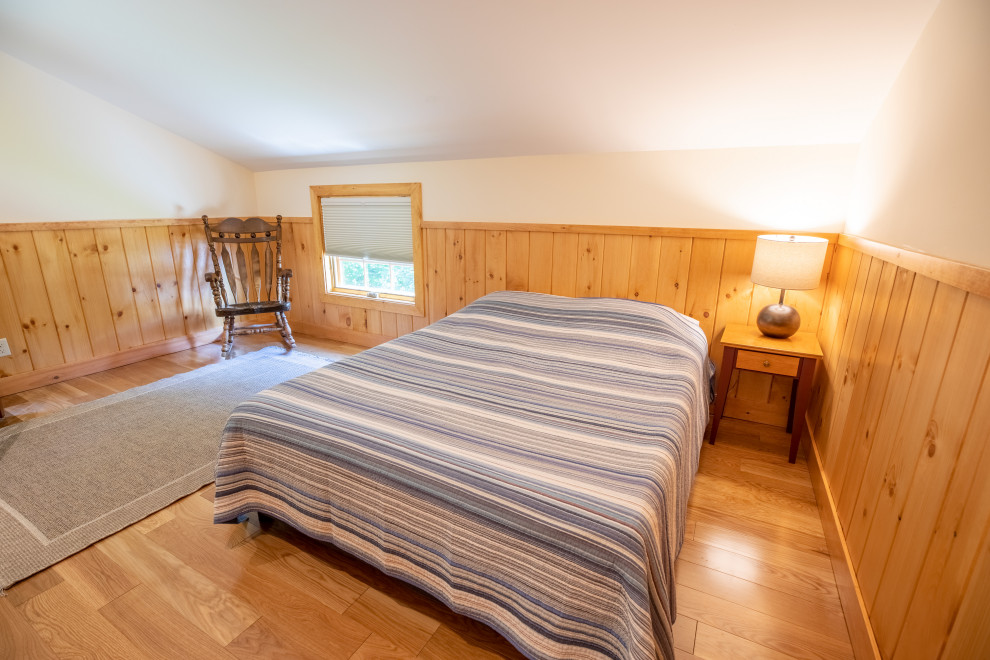 Foto de habitación de invitados rústica de tamaño medio sin chimenea con suelo de madera clara, suelo beige, paredes beige, techo inclinado y boiserie