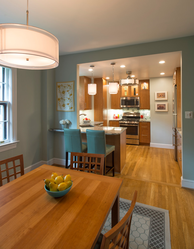 This is an example of a small transitional u-shaped eat-in kitchen in DC Metro with an undermount sink, flat-panel cabinets, medium wood cabinets, granite benchtops, green splashback, glass tile splashback, stainless steel appliances, light hardwood floors and no island.