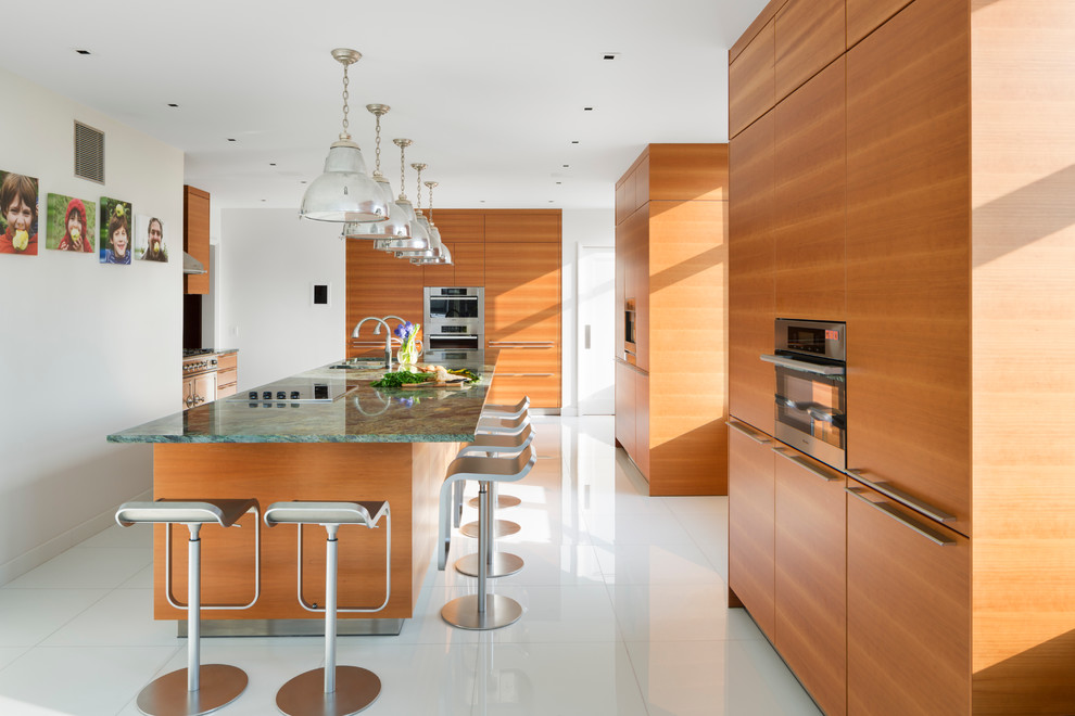 Photo of a contemporary kitchen in New York with flat-panel cabinets, medium wood cabinets, granite benchtops, porcelain floors, with island, an undermount sink, stainless steel appliances, white floor and green benchtop.