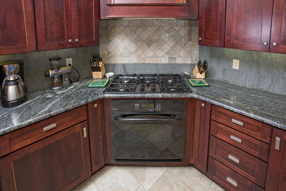 Inspiration for a large transitional l-shaped porcelain tile open concept kitchen remodel in Denver with an undermount sink, shaker cabinets, red cabinets, granite countertops, gray backsplash, stone tile backsplash, black appliances and an island