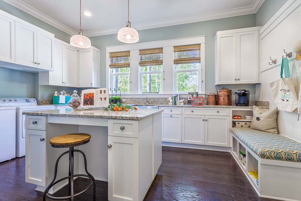 This is an example of an expansive traditional u-shaped utility room in Other with a farmhouse sink, shaker cabinets, white cabinets, granite benchtops, blue walls, dark hardwood floors, a side-by-side washer and dryer and brown floor.