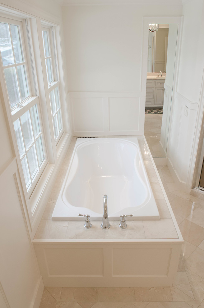 Design ideas for a mid-sized traditional master bathroom in Minneapolis with an undermount sink, beaded inset cabinets, white cabinets, marble benchtops, a drop-in tub, a corner shower, a two-piece toilet, beige tile, stone tile, white walls and marble floors.