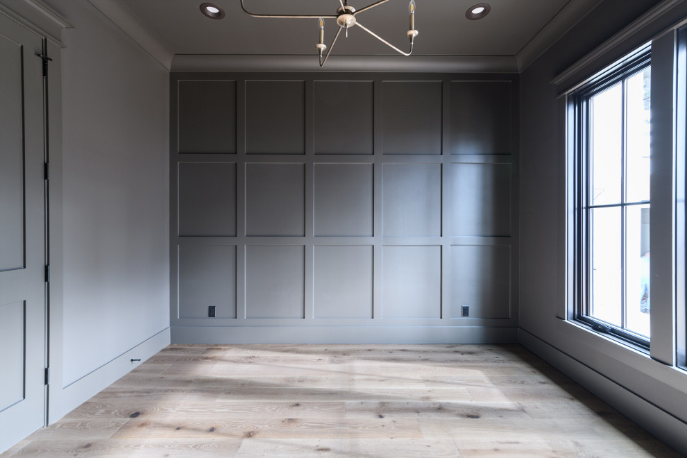 На фото: кабинет в скандинавском стиле с серыми стенами, бежевым полом и панелями на части стены с