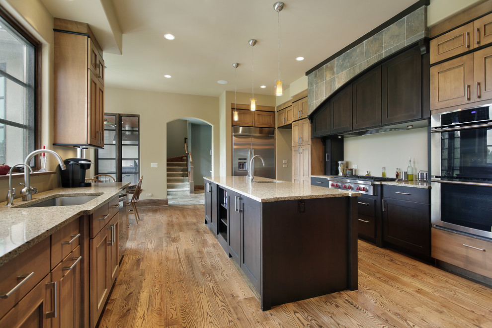 Inspiration for a large transitional galley dark wood floor and brown floor eat-in kitchen remodel with an undermount sink, beaded inset cabinets, distressed cabinets, quartz countertops, stainless steel appliances and an island
