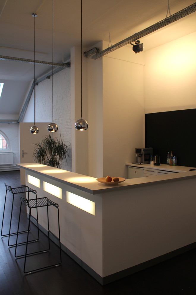 This is an example of a small modern u-shaped open plan kitchen in Berlin with white cabinets, dark hardwood floors and a peninsula.