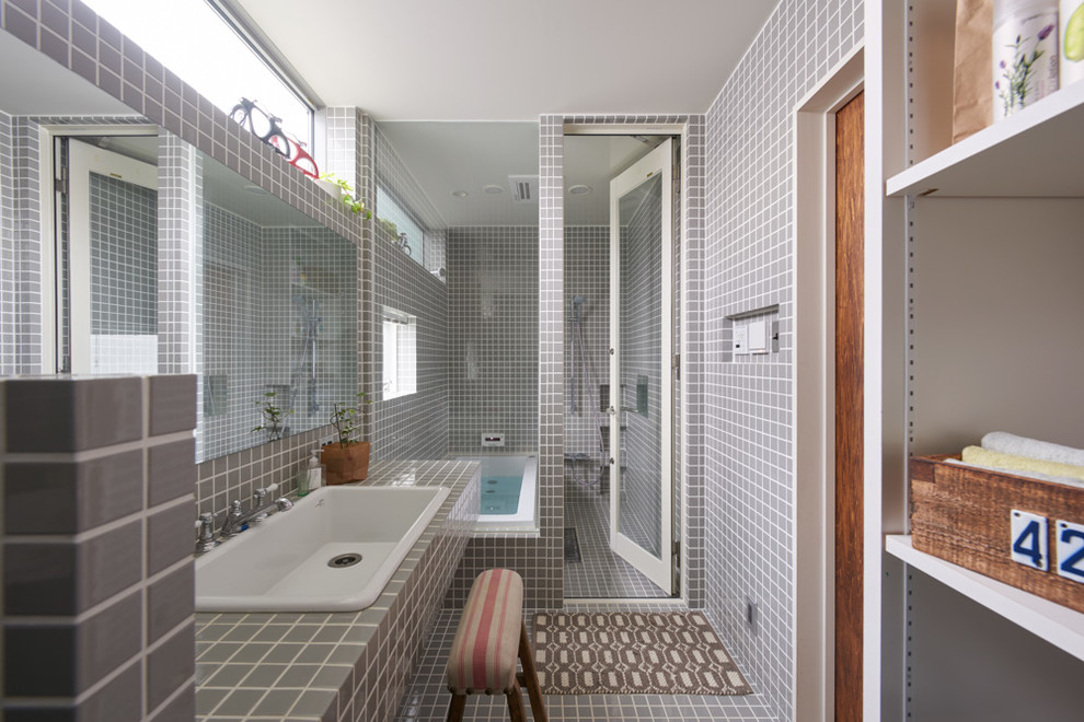 Traditional master bathroom in Tokyo Suburbs with open cabinets, white cabinets, a drop-in tub, gray tile, porcelain tile, grey walls, porcelain floors, a drop-in sink, tile benchtops and a hinged shower door.