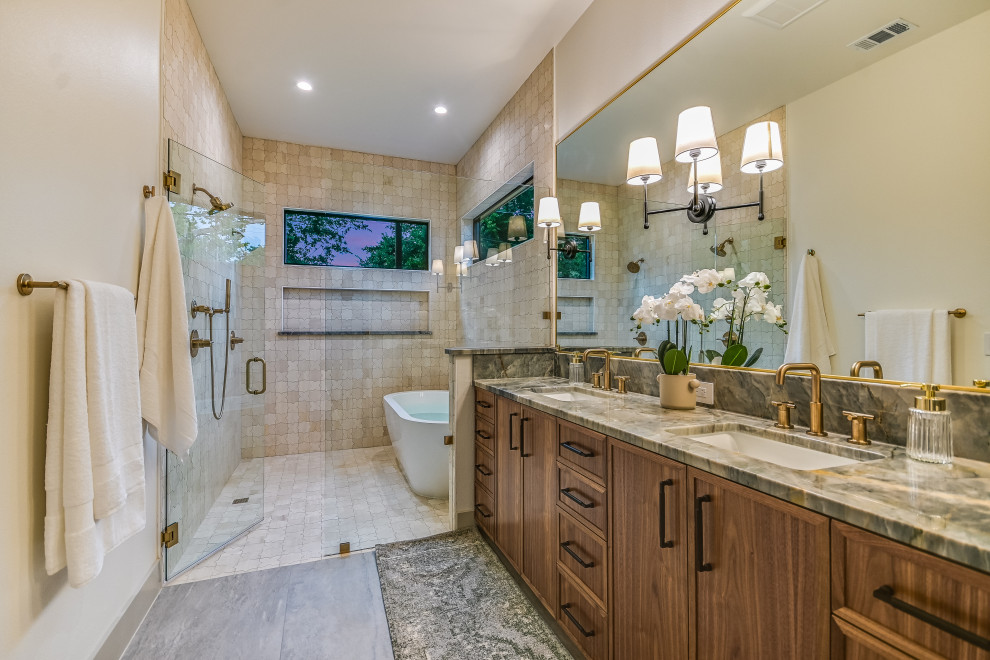 Freestanding bathtub - transitional master beige tile and stone tile ceramic tile, gray floor and double-sink freestanding bathtub idea in Austin with recessed-panel cabinets, medium tone wood cabinets, white walls, an undermount sink, quartz countertops, a hinged shower door, gray countertops and a built-in vanity