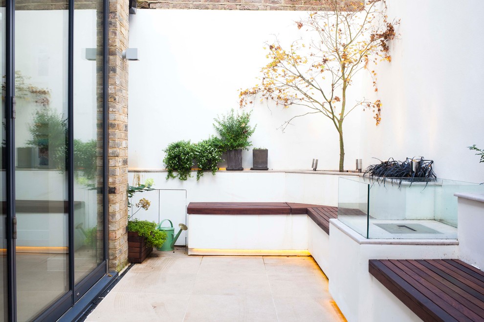 Design ideas for a small contemporary backyard patio in London with a fire feature.