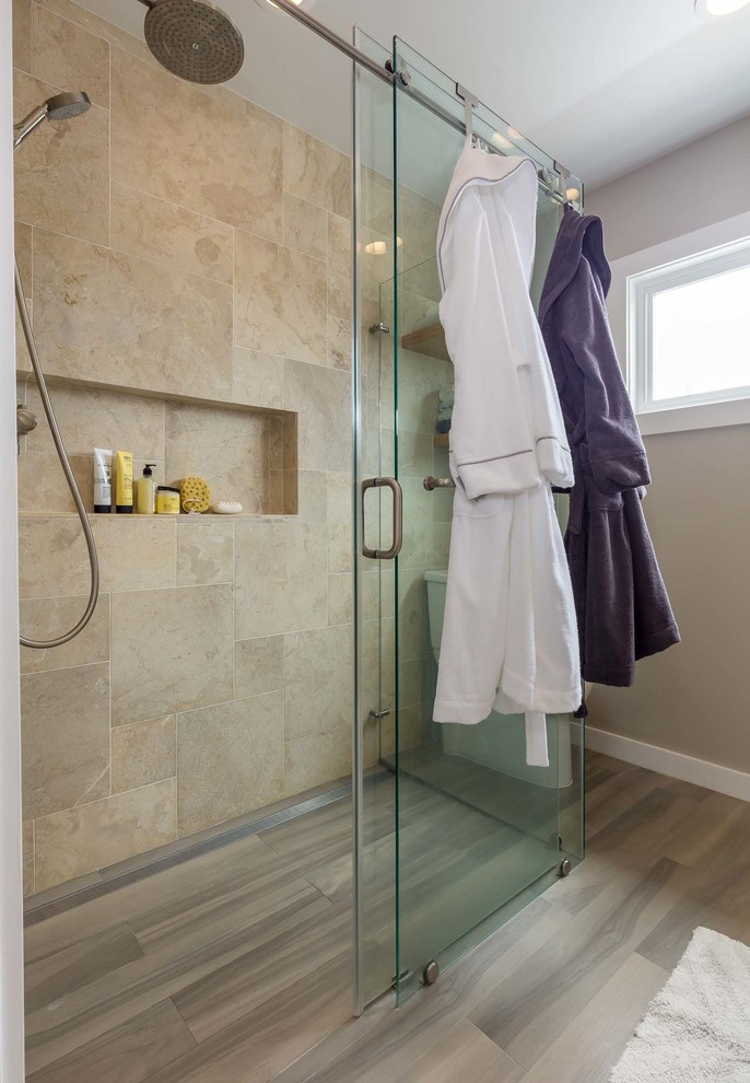 Photo of a mid-sized contemporary master bathroom in Los Angeles with flat-panel cabinets, light wood cabinets, a curbless shower, a two-piece toilet, beige tile, travertine, beige walls, porcelain floors, a vessel sink, engineered quartz benchtops, brown floor and a sliding shower screen.