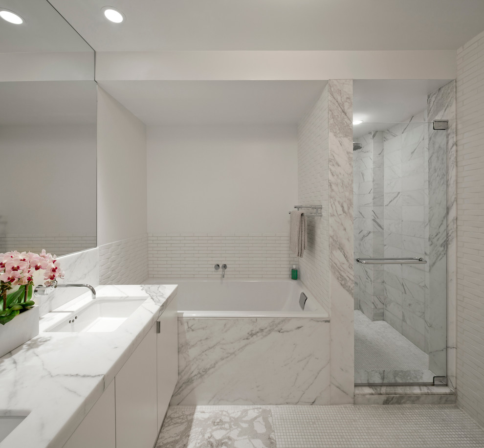 Design ideas for a large modern master bathroom in New York with marble benchtops, marble, flat-panel cabinets, white cabinets, a drop-in tub, an alcove shower, gray tile, white walls, marble floors, an undermount sink, grey floor, a hinged shower door and grey benchtops.