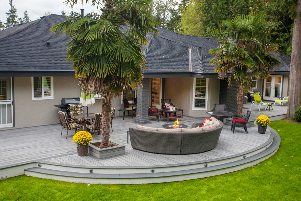 Inspiration for an expansive modern backyard deck in Vancouver with a fire feature and a roof extension.