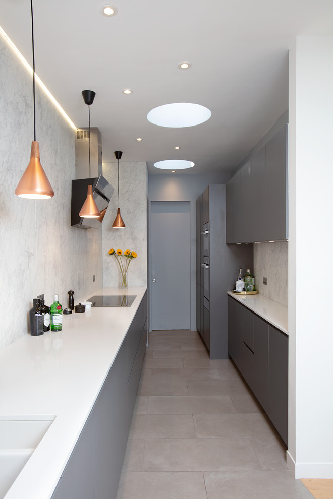 Mid-sized contemporary galley separate kitchen in London with a double-bowl sink, flat-panel cabinets, grey cabinets, white splashback, marble splashback, no island, grey floor, white benchtop and panelled appliances.