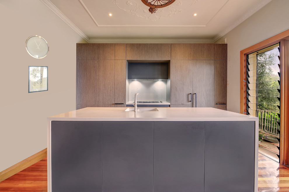 Inspiration for a mid-sized contemporary galley eat-in kitchen in Sydney with an undermount sink, flat-panel cabinets, grey cabinets, quartz benchtops, white splashback, stone slab splashback, stainless steel appliances, medium hardwood floors, with island, brown floor and white benchtop.