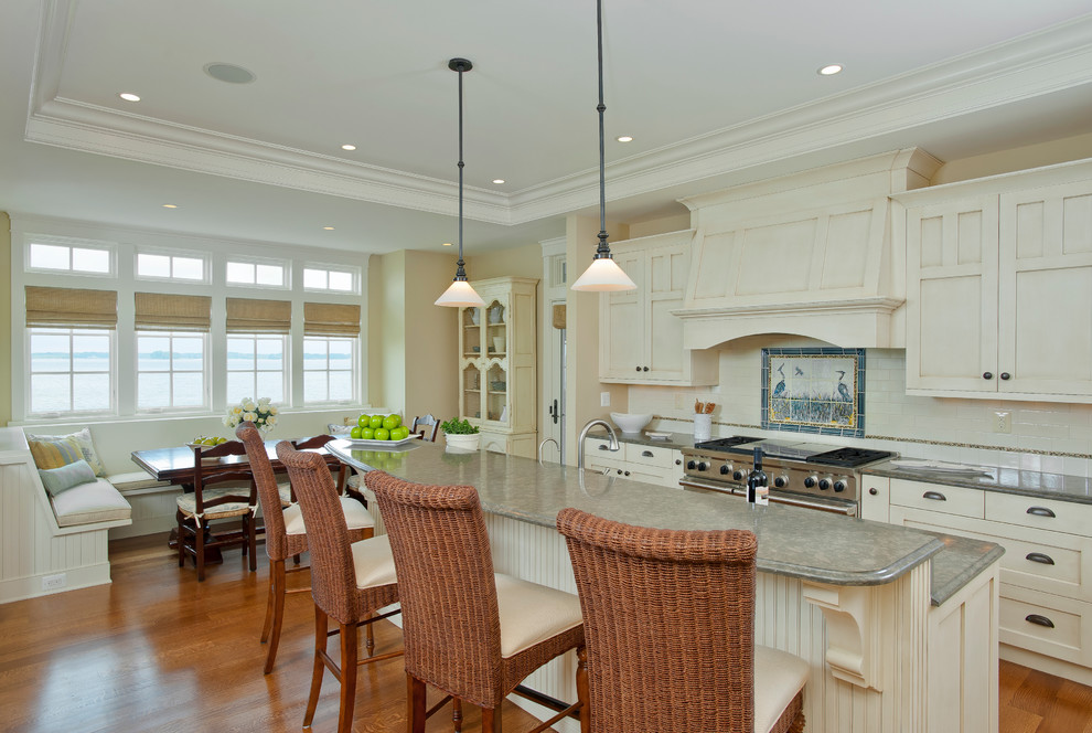 Inspiration for a beach style eat-in kitchen in Baltimore with shaker cabinets, white cabinets, beige splashback, ceramic splashback, stainless steel appliances, medium hardwood floors and with island.