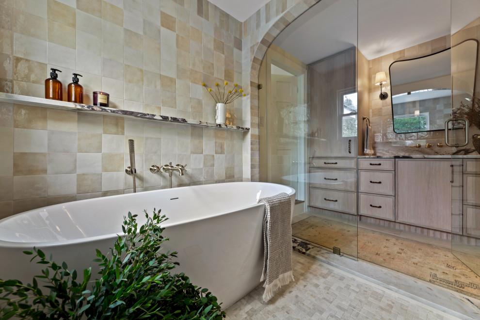 Example of a large transitional master beige tile and porcelain tile porcelain tile, beige floor and single-sink drop-in bathtub design in Austin with shaker cabinets, light wood cabinets, a two-piece toilet, white walls, an undermount sink, marble countertops, a hinged shower door, brown countertops, a niche and a built-in vanity