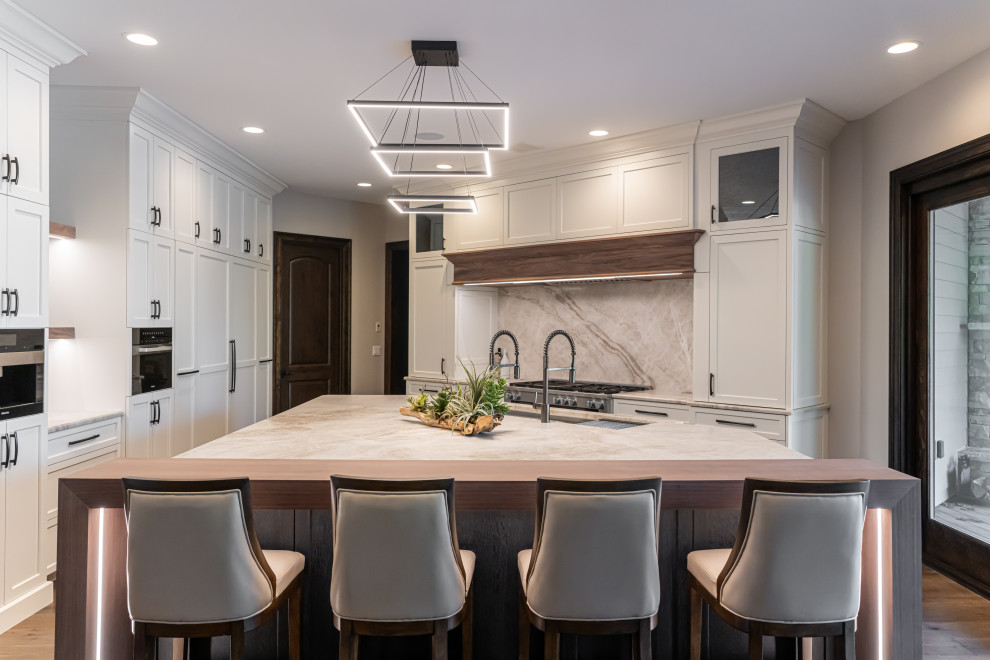 Example of a large transitional medium tone wood floor and brown floor open concept kitchen design with a double-bowl sink, flat-panel cabinets, white cabinets, quartzite countertops, beige backsplash, stainless steel appliances, an island and beige countertops