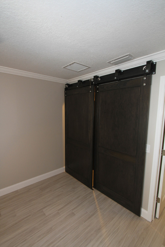 Photo of a transitional storage and wardrobe in Orlando with recessed-panel cabinets, dark wood cabinets and porcelain floors.